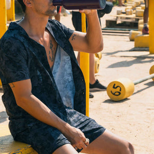 Man at an outdoor gym in a Street Camo resort shirt and matching camouflage hybrid swim shorts