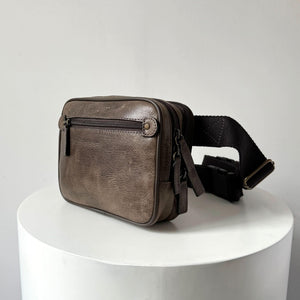 Brown leather waist bag on a white pedestal with a light gray background