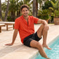 Man wearing the Dark Coral resort set, Coral button down resort shirt open over Black Onyx hybrid swim shorts