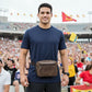 Man wearing a brown fanny pack at a sports event with a crowd in the background