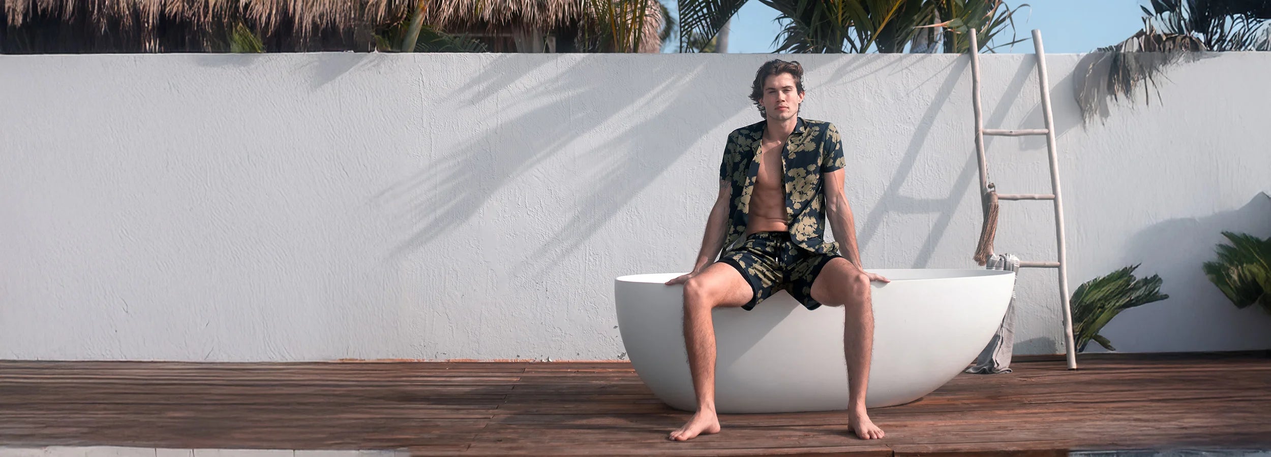 guy sitting on the top outside while wearing matching shirt and swim trunks set