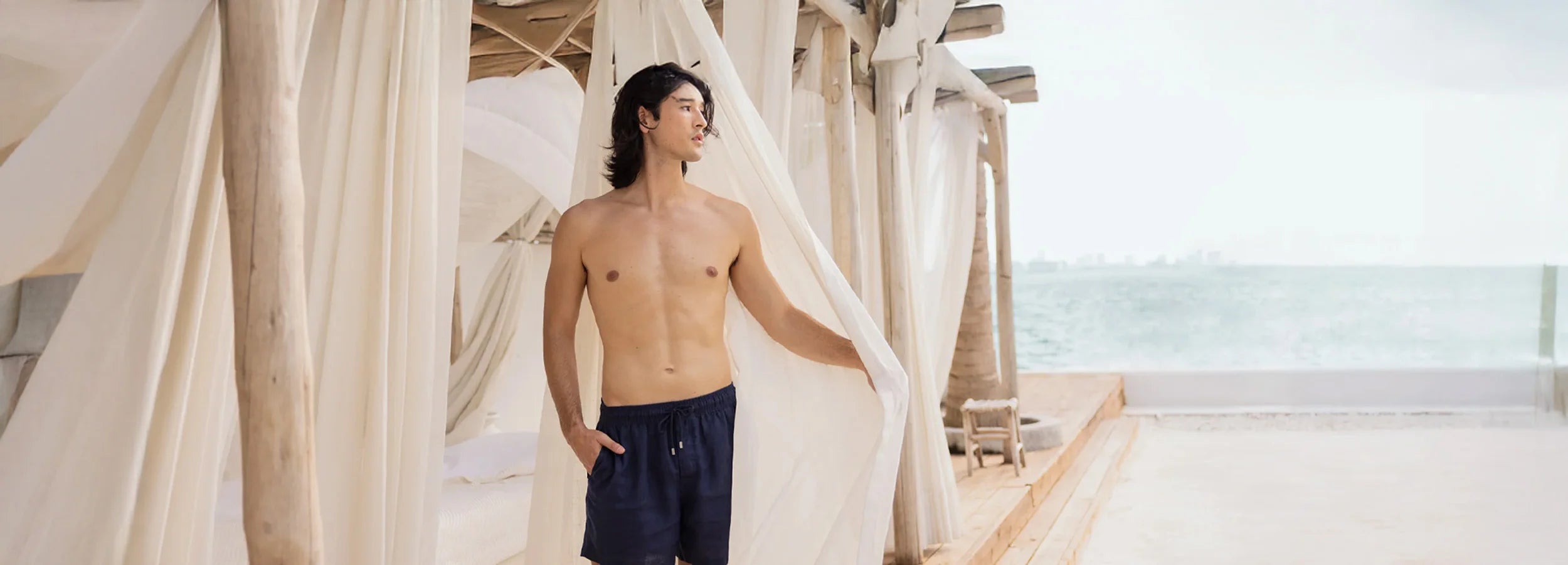 asian guy looking into the distance while wearing navy linen shorts