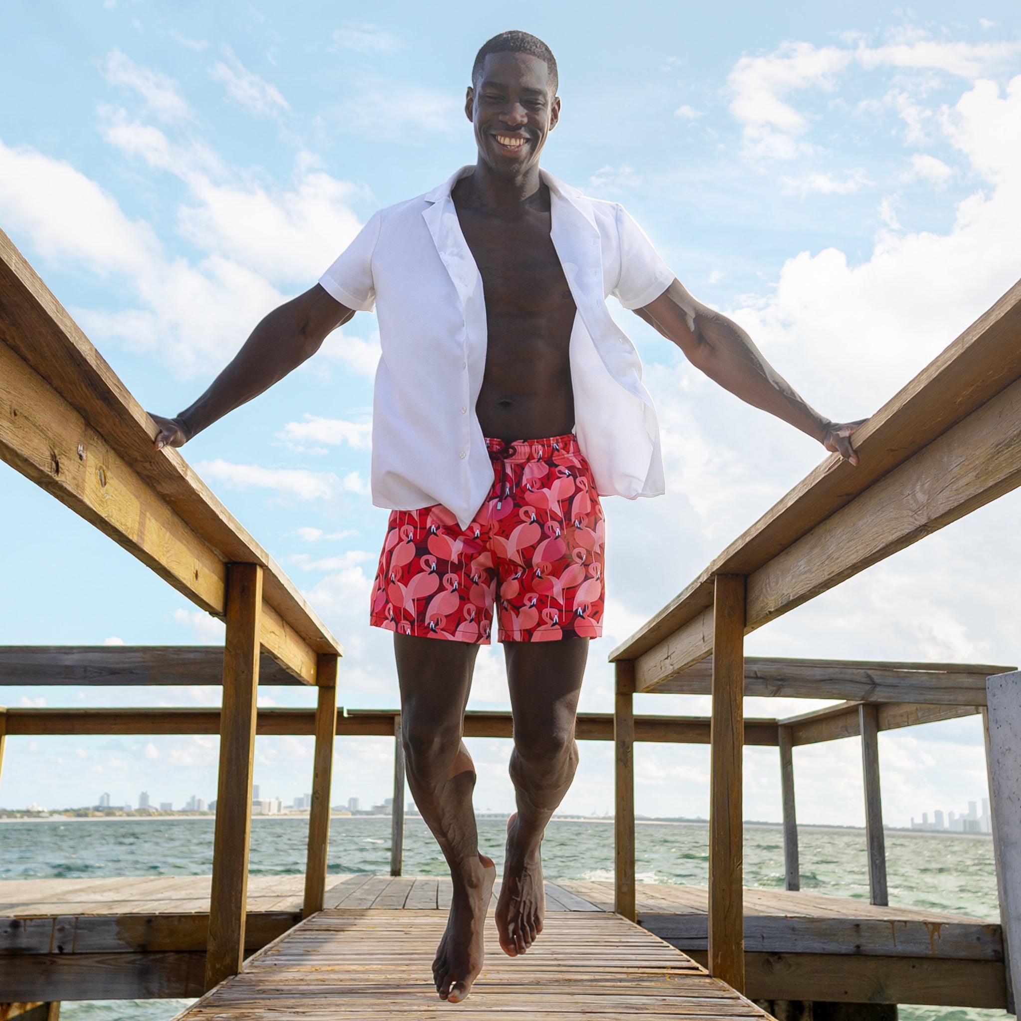 Man in an Arctic White resort shirt worn open over Pink Flamingo hybrid swim shorts