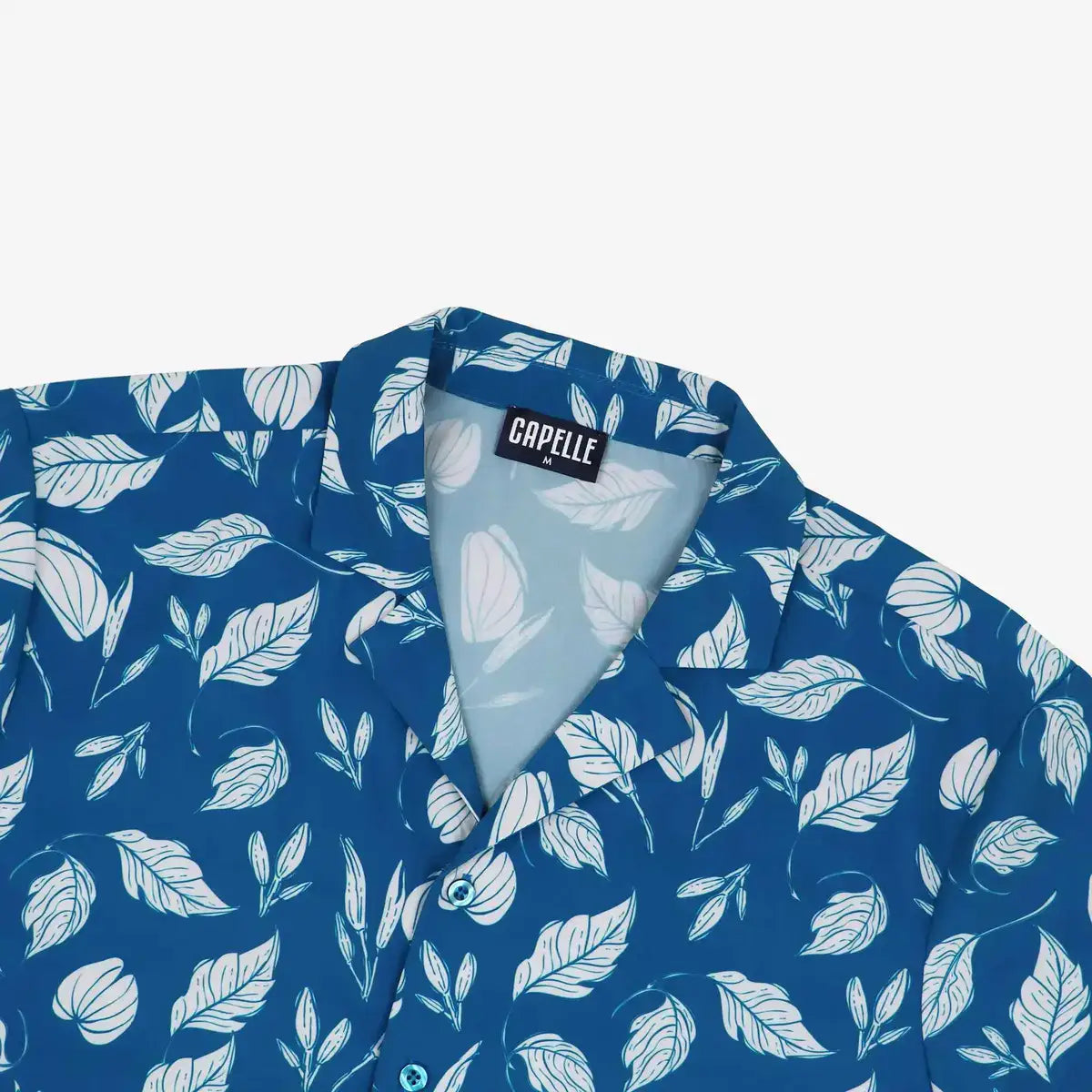 Close-up of the Autumn Blue resort shirt fabric, teal blue with a white leaf print