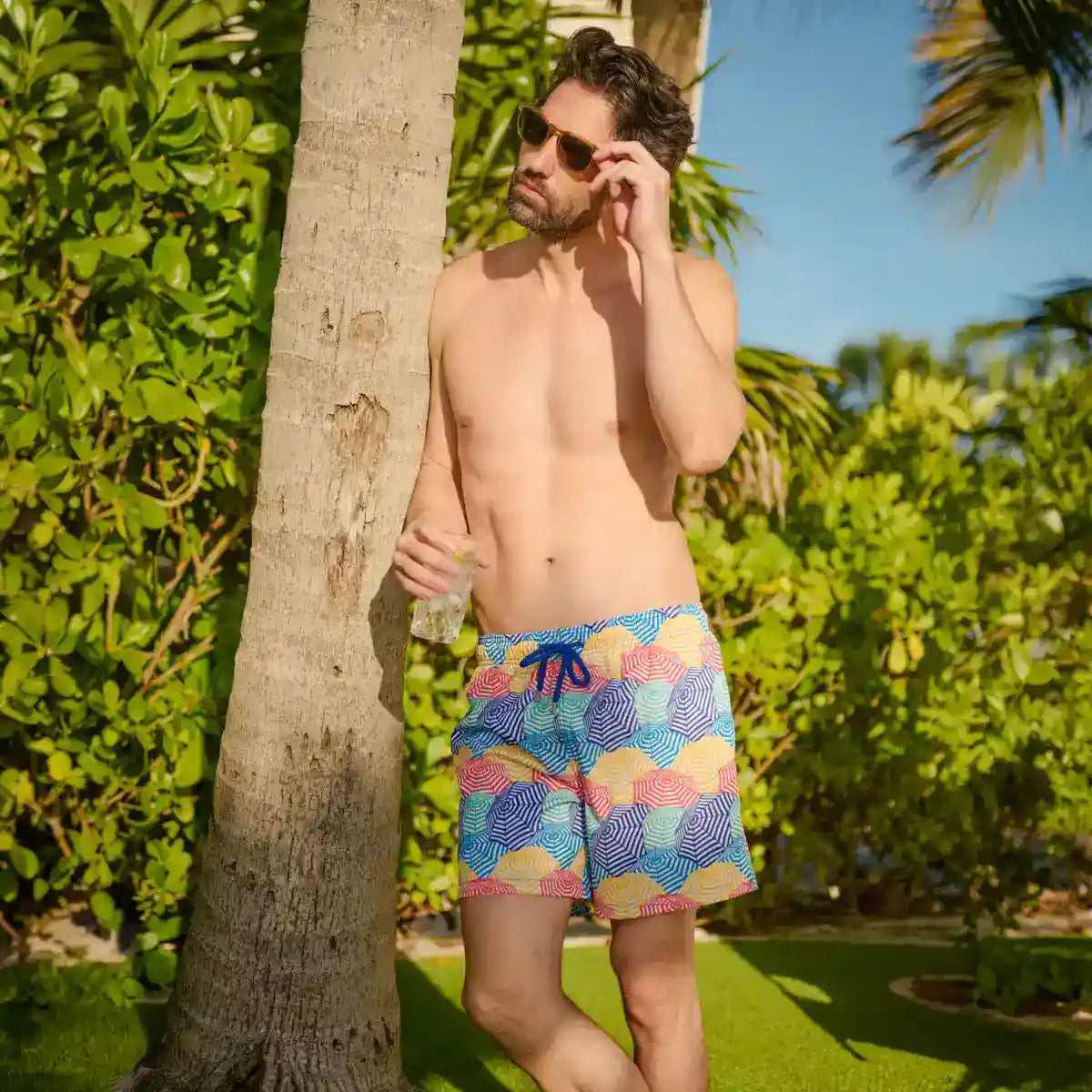 Man in Bayside Shade Splash hybrid swim shorts, a multicolor beach umbrella print, outdoors