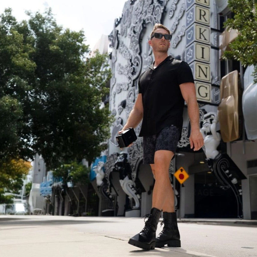 Man on a city street in a Black Onyx resort shirt and Street Camo hybrid swim shorts