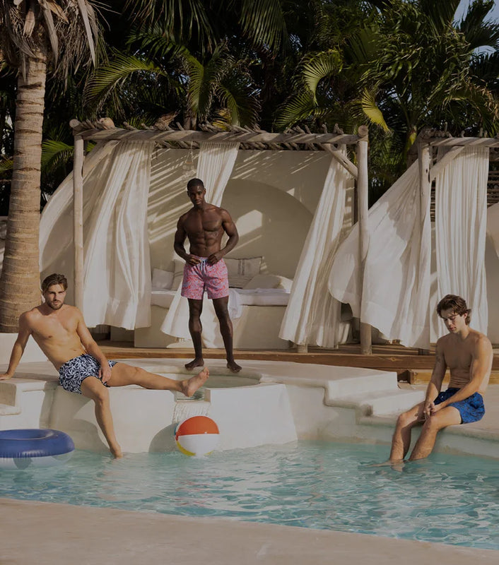 3 men in swim trunks by the pool