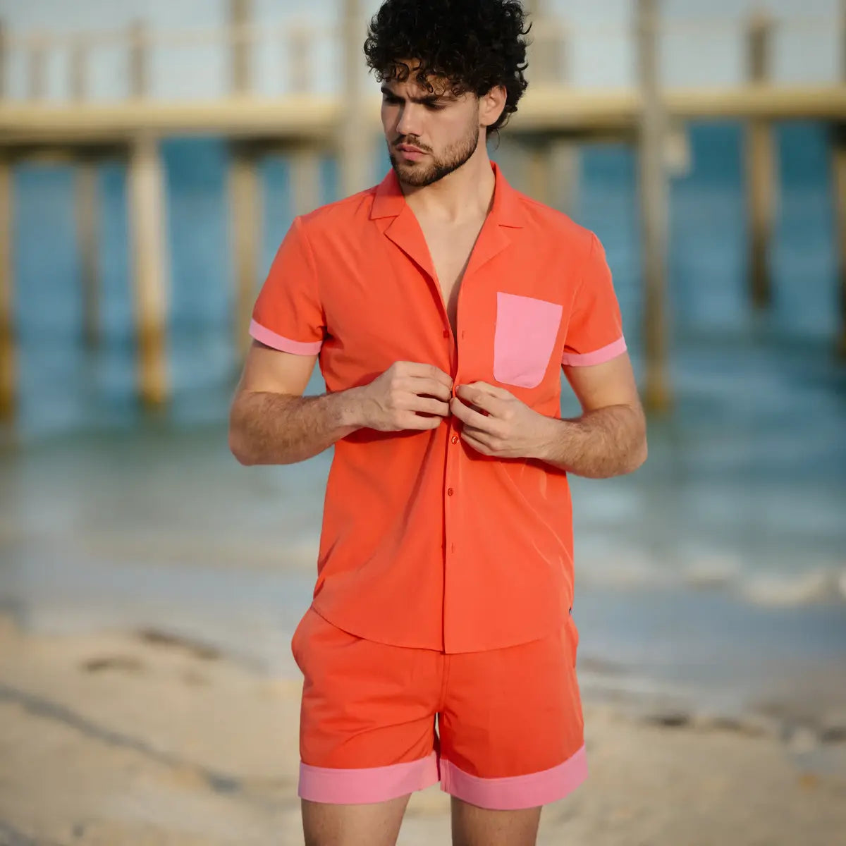 Man in a Coral Flame resort shirt and matching hybrid swim shorts, coral orange with pink contrast trim
