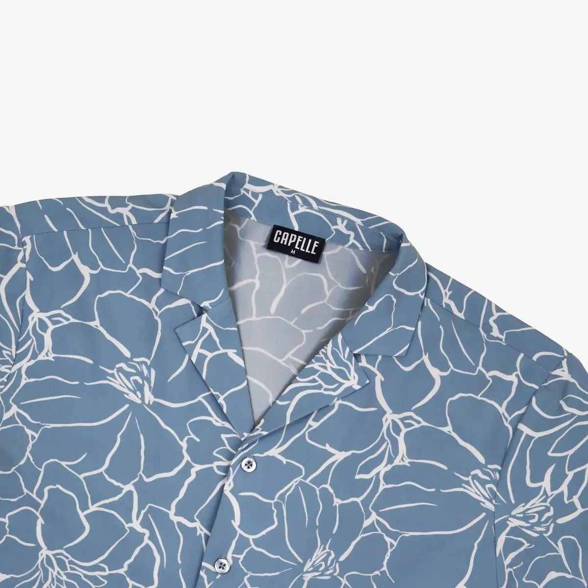 Close-up of the Early Bloom resort shirt fabric, dusty blue with a white floral outline print