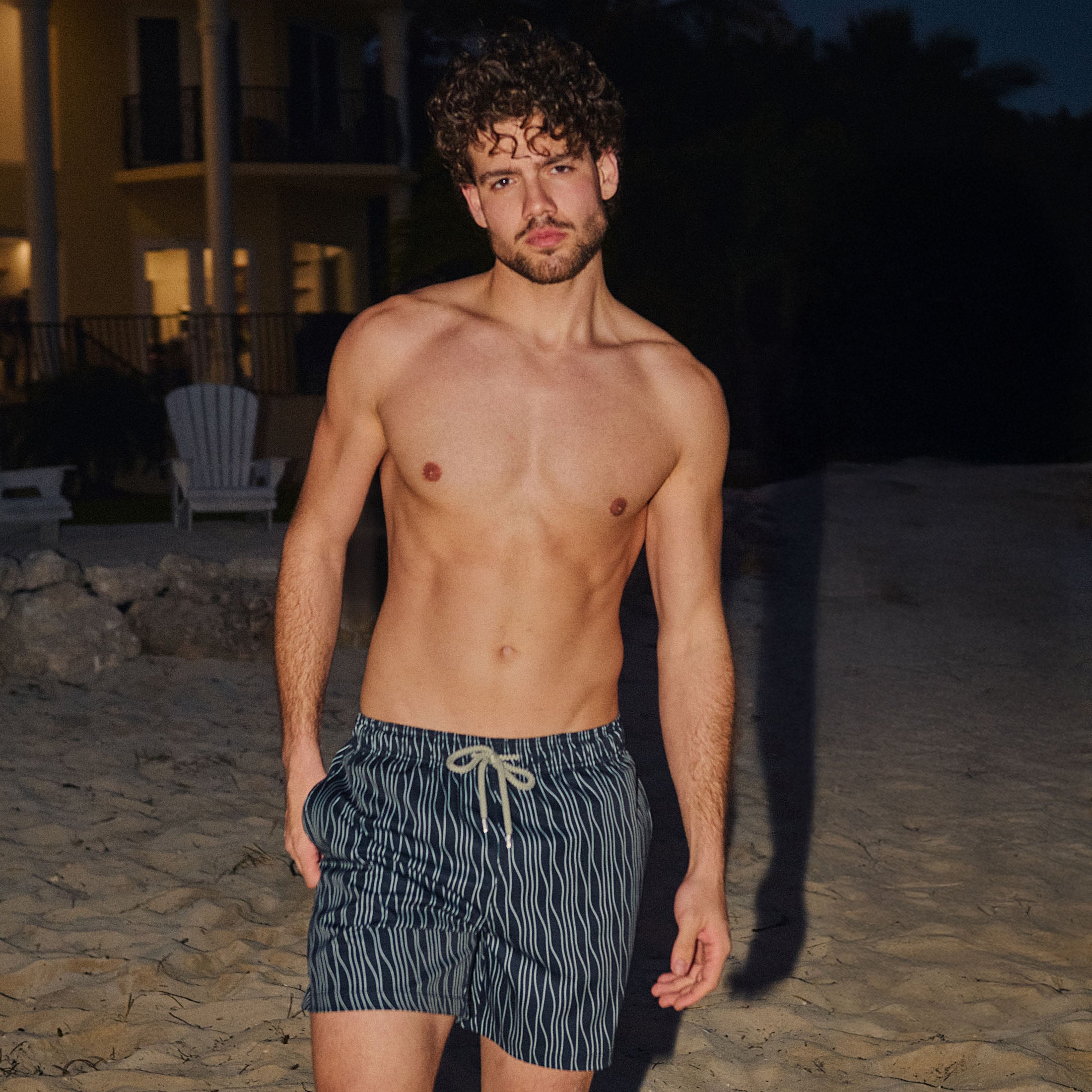 Man in Linear Drift Storm and Fog hybrid swim shorts, charcoal with a white wave stripe, outdoors