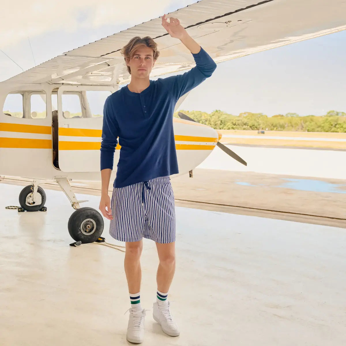 Man in Marina Pinstripe Indigo and Surf hybrid swim shorts, navy and white pinstripe, at the water