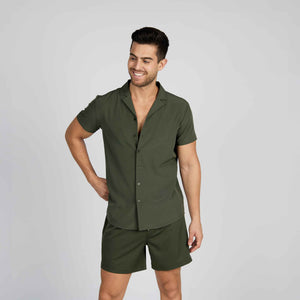 Man in an Olive You resort shirt and matching dark olive shorts, studio view