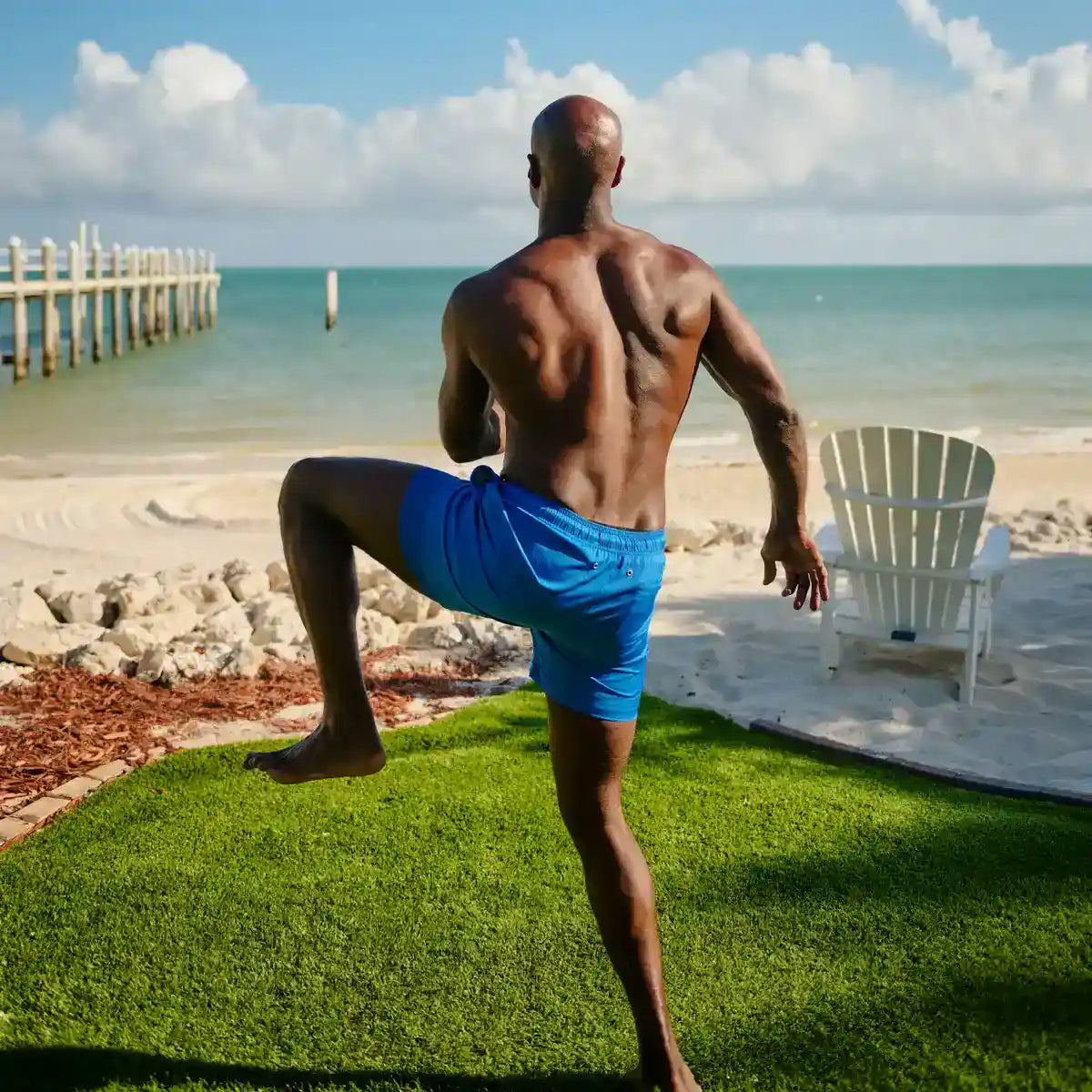 Man in Ocean Blue hybrid swim shorts, solid ocean blue, outdoors at the water