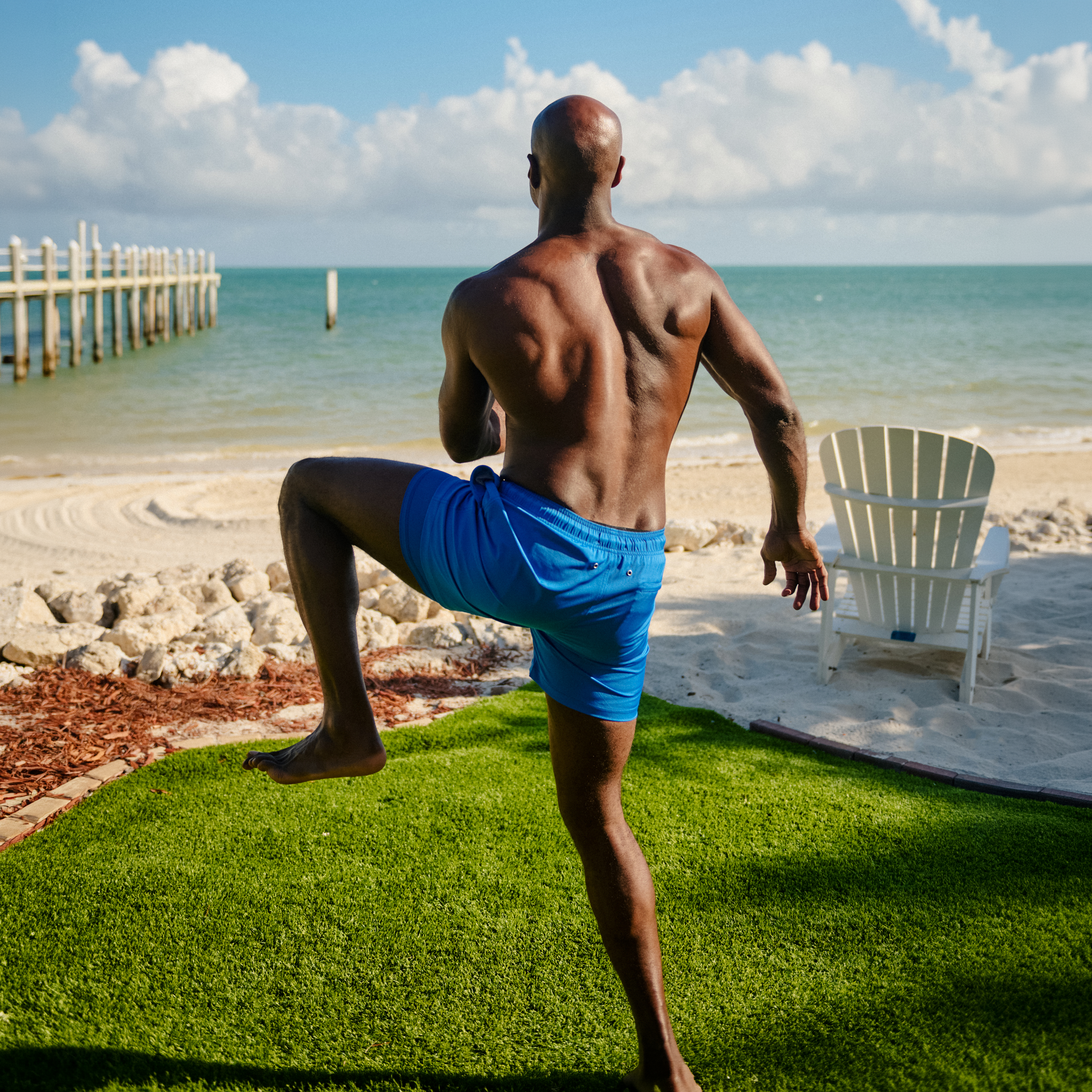 Man in Ocean Blue hybrid swim shorts, solid ocean blue, at the water