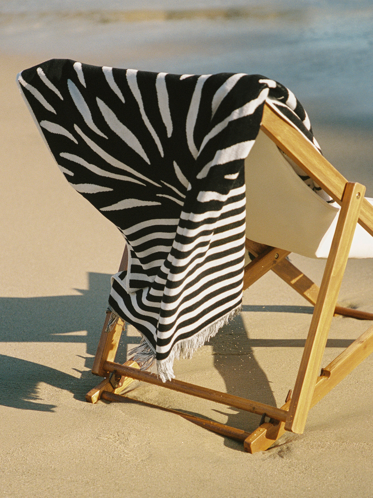 Ruby Mint Remington black and white floral stripe towel on a wooden beach chair