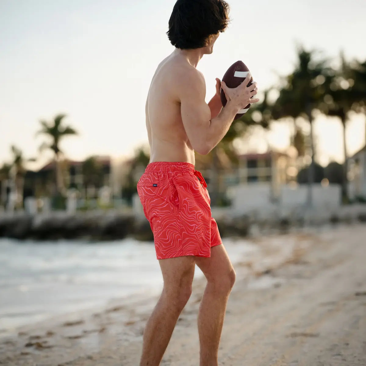 Man in Sand Waves Heat and Bloom hybrid swim shorts, coral with a tonal wave line print