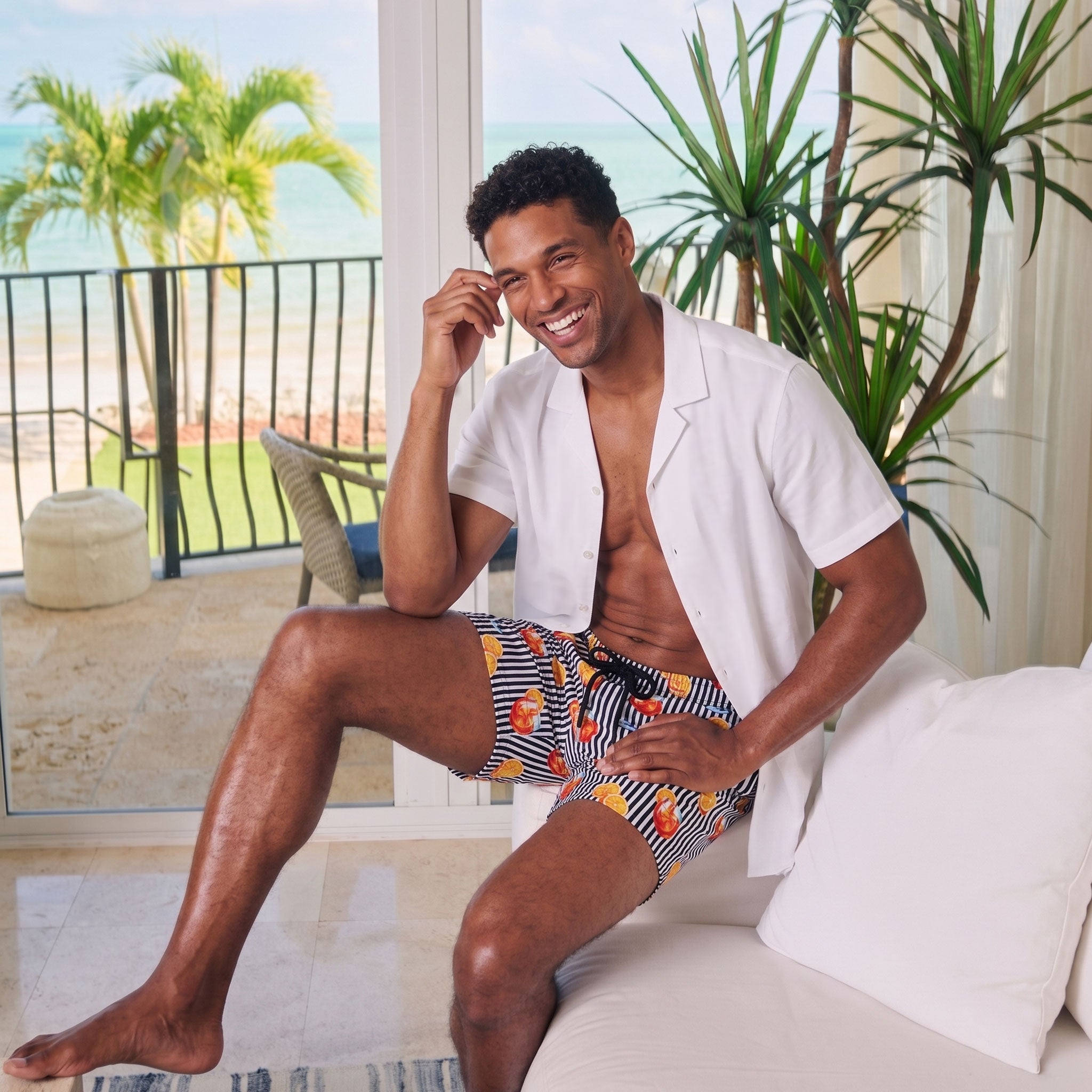 Man in an Arctic White resort shirt worn open over Sunset Spritz Surf and Storm hybrid swim shorts