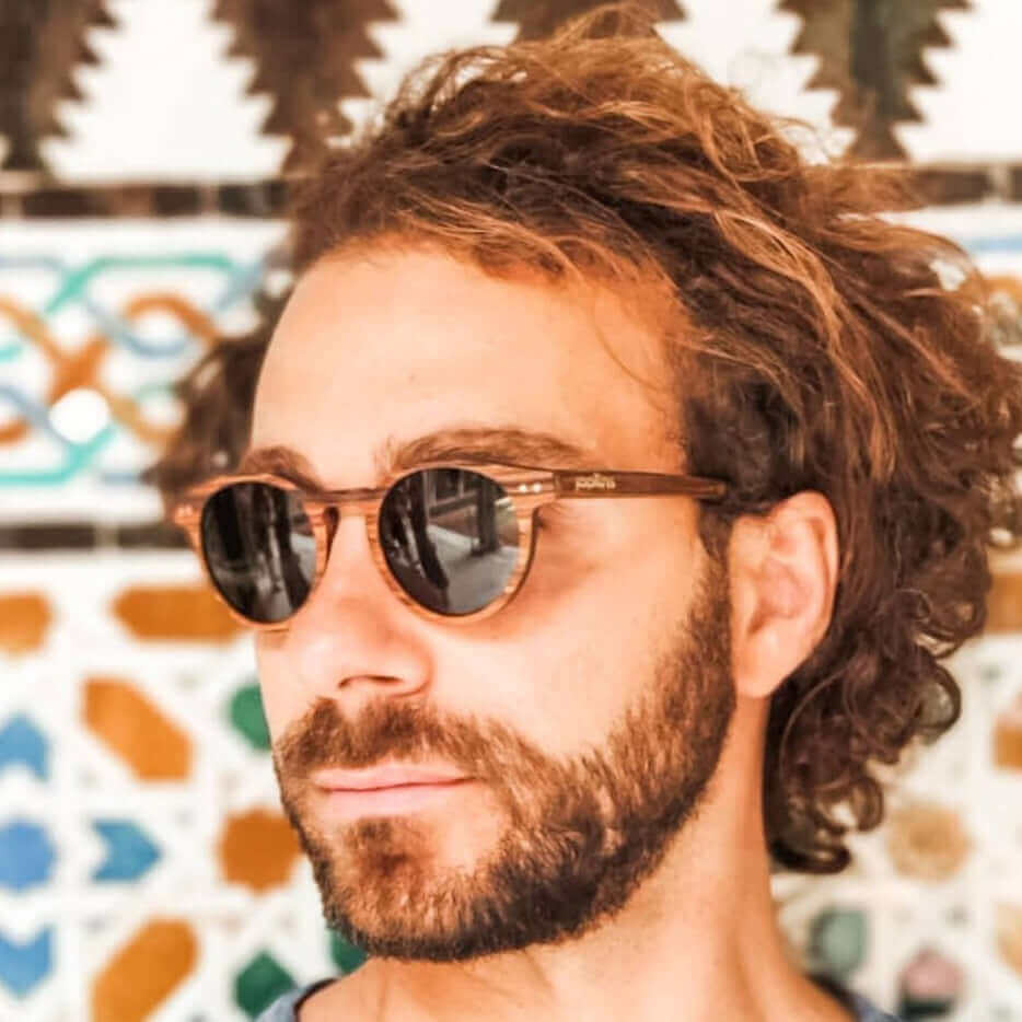 Man in JOPLINS Stinson polarized round wooden sunglasses against tall grass