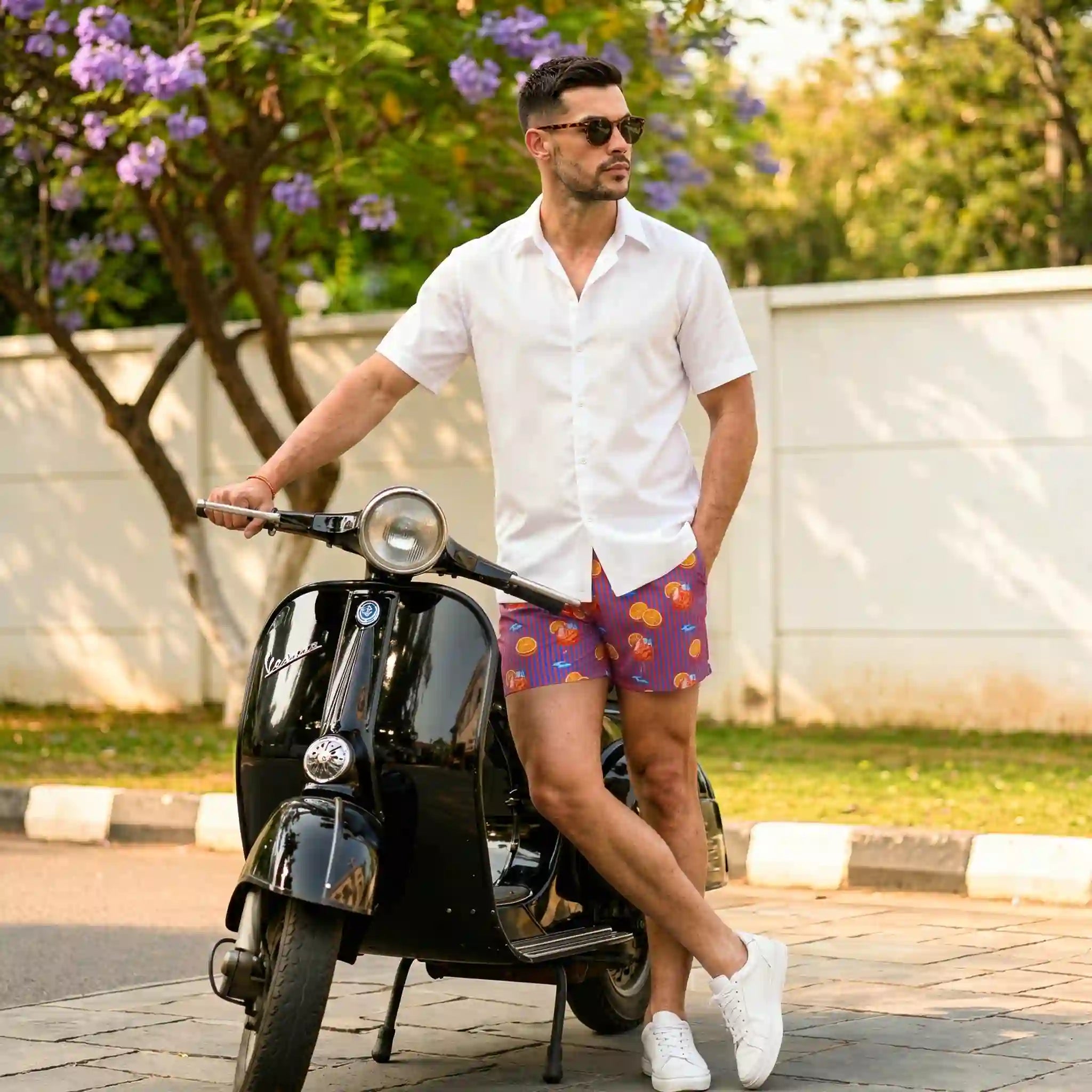 Man beside a vintage scooter in Sunset Spritz Ocean and Heat hybrid swim shorts and a white resort shirt