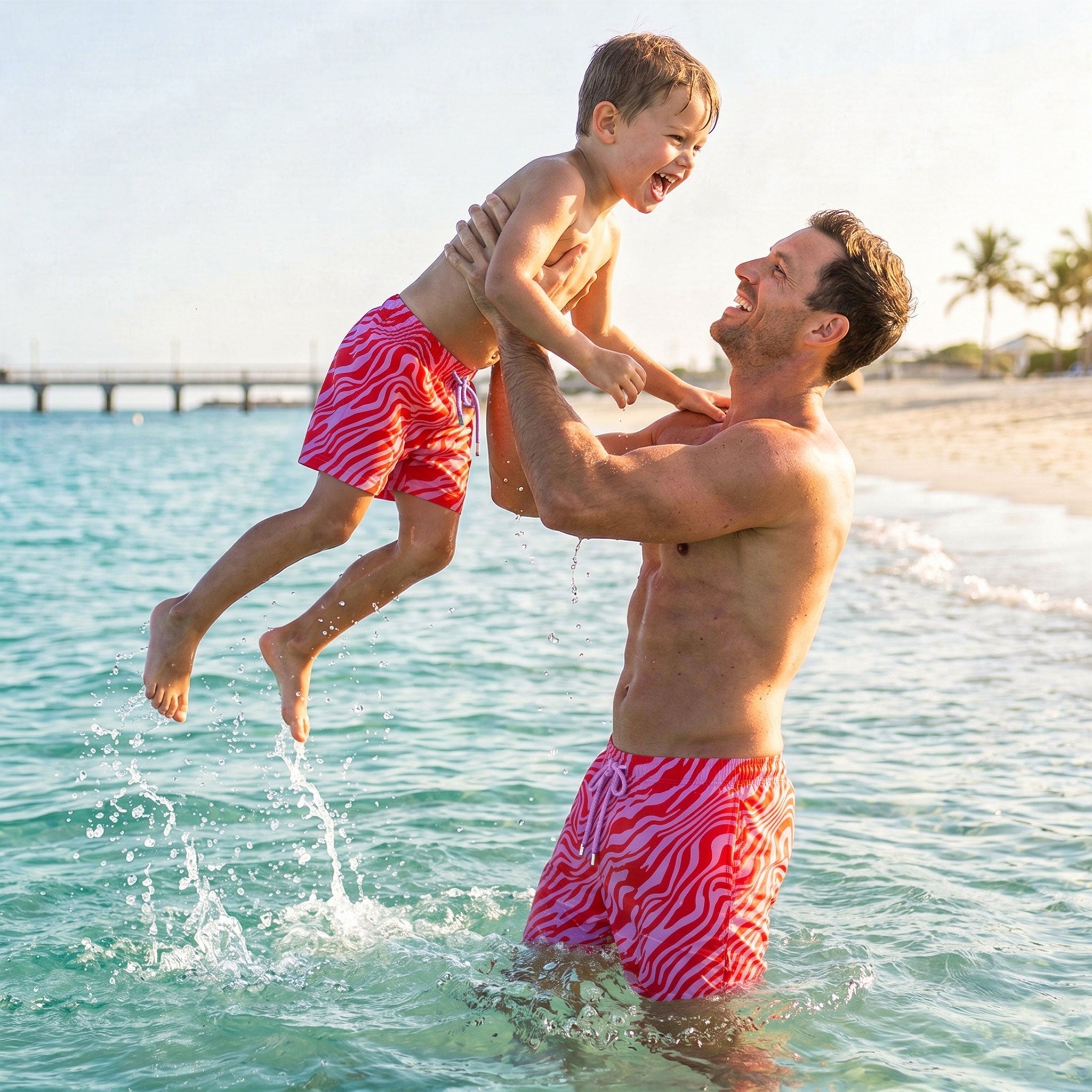 Man and boy in matching Tropical Swirl Coral and Orchid hybrid swim shorts