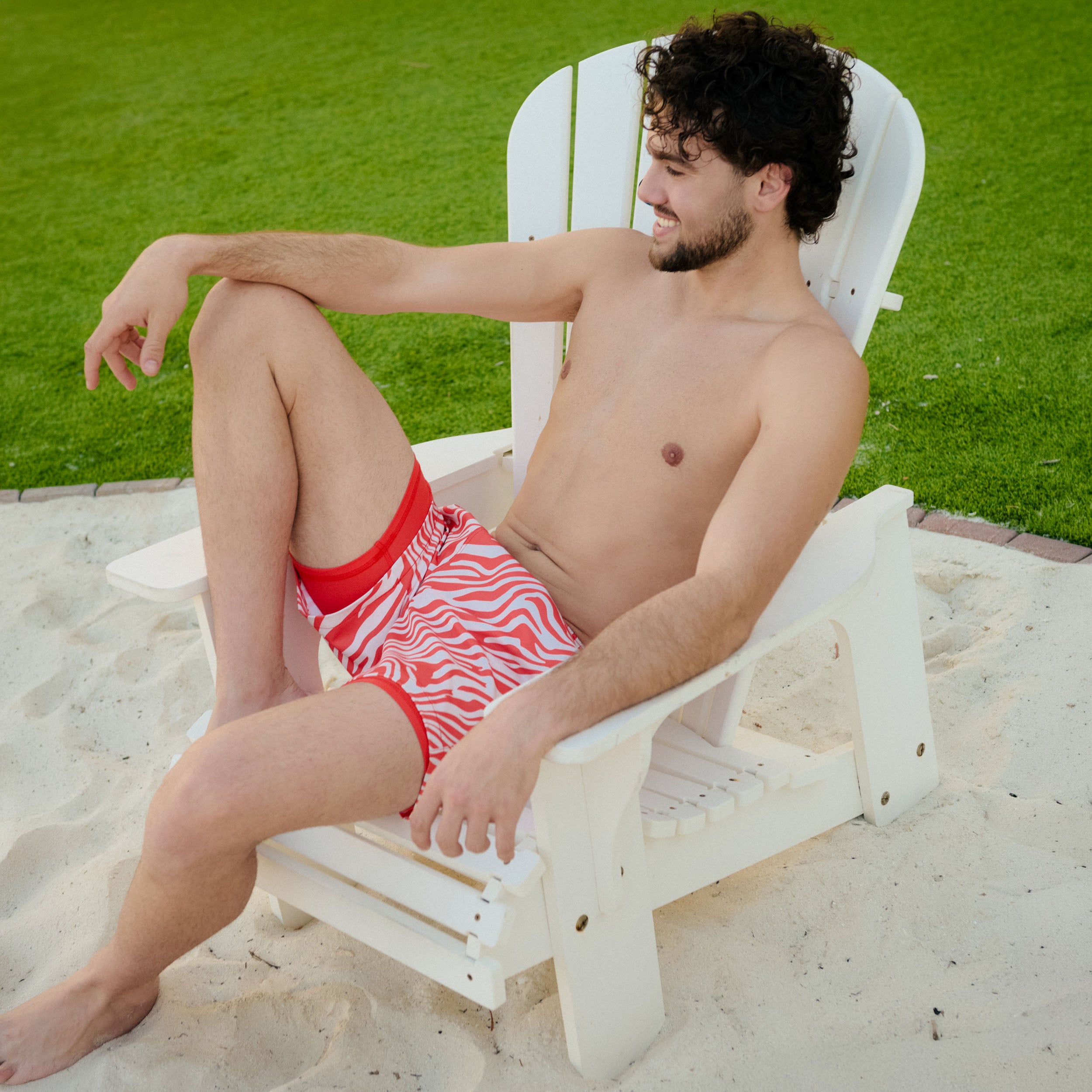 Man in Tropical Swirl Ocean and Palm hybrid swim shorts, blue and green swirled print, outdoors