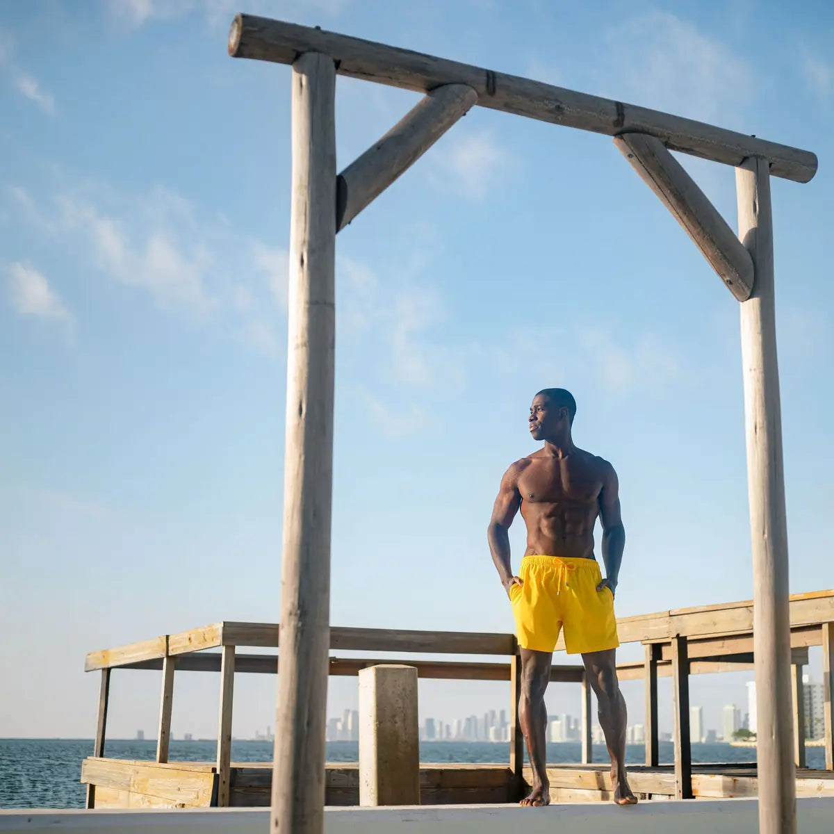 Man in True Yellow hybrid swim shorts, solid bright yellow, at the water